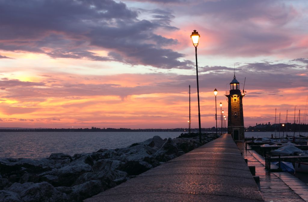 Colorful Sunrise at Desenzano del Garda with the marina and the old Lighthouse.